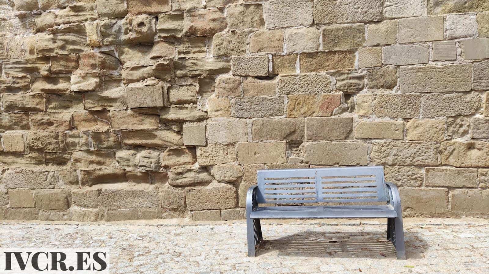 a bench sitting in front of a stone wall